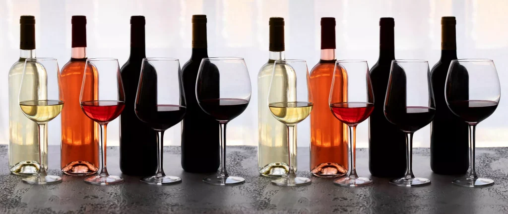 otto bottiglie di vino di diversi tipi: bianco, rosa e rosso, otto bicchieri con vino versato