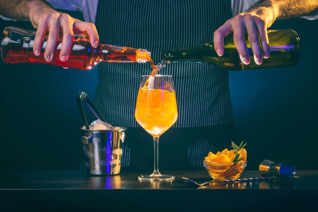 barman nalewający aperol i prosecco do kieliszka na aperitif aperol spritz