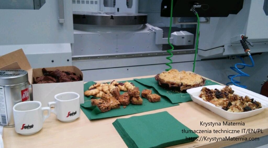 pomieszczenie przemysłowe, obrabiarka CNC i stół, na którym stoją słodycze, ciastka i filiżanki kawy
