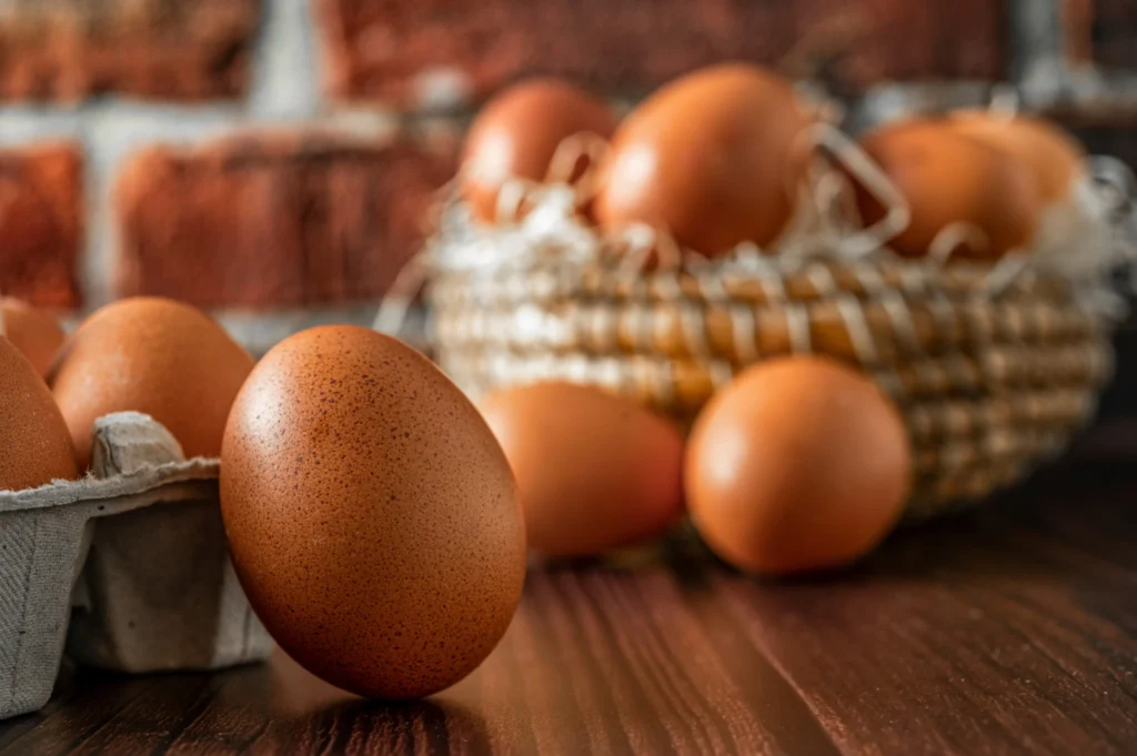 świeże jaja na drewnianym blacie oraz w wiklinowym koszyku