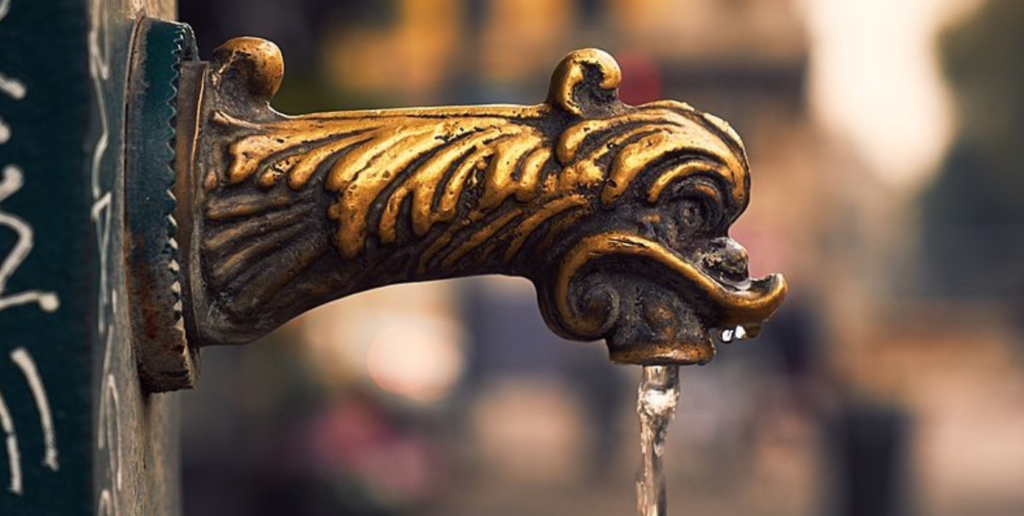 Mosiężny kurek fontanny vedovella w Mediolanie, z którego leje się woda